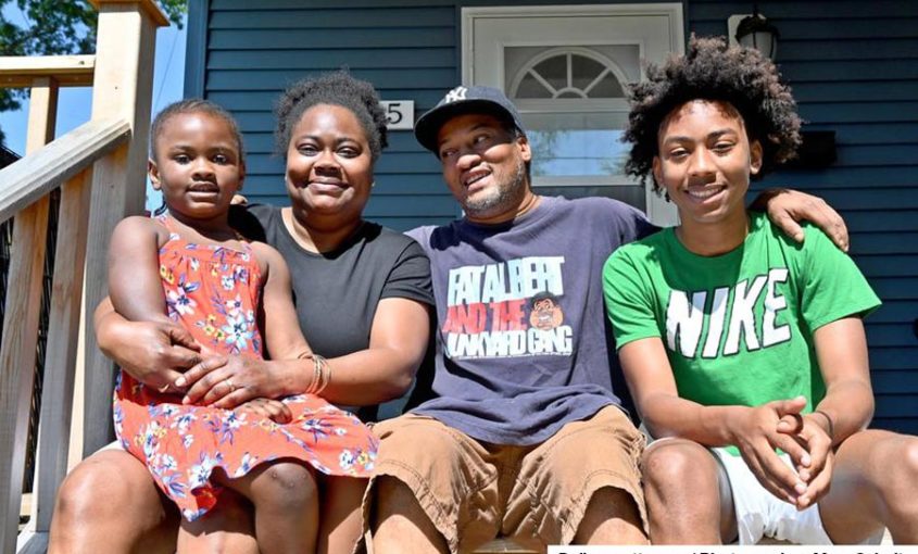 New Habitat homeowners smiling on the porch of their home